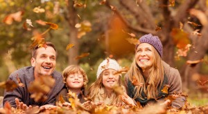 Familiy playing in a pile of leaves during the fall
